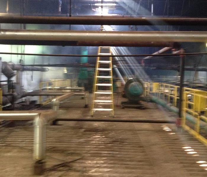 Industrial flooring that is very dirty, dirty pipes and a ladder