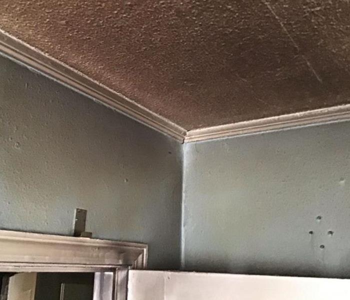Light blue walls with white ceiling both covered with soot from a fire