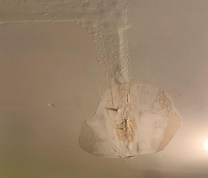 Bedroom ceiling that is ready to fall due to water that has formed in the attic