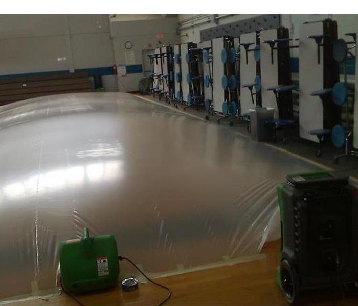 School gym floor that has water damage and is being mitigated to remove the water