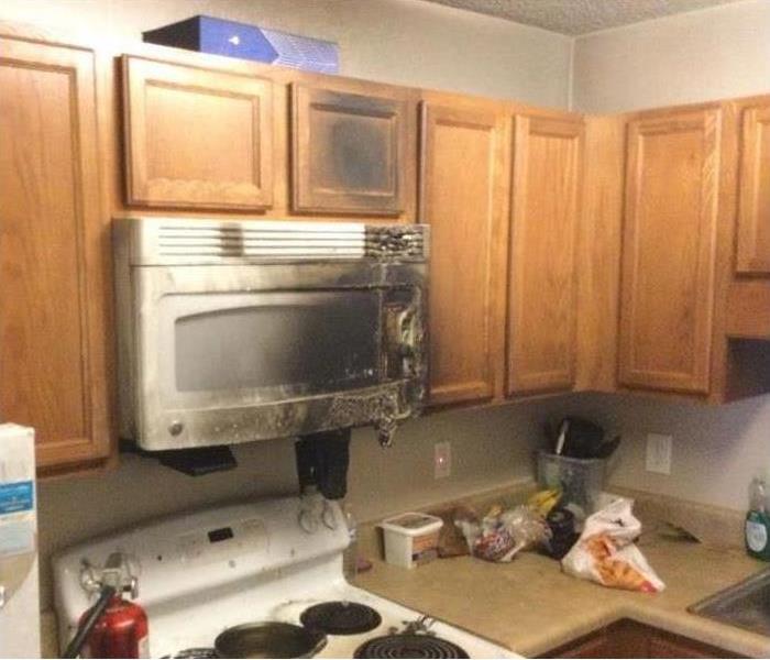 Kitchen stove with microwave above it has been burned from a grease fire